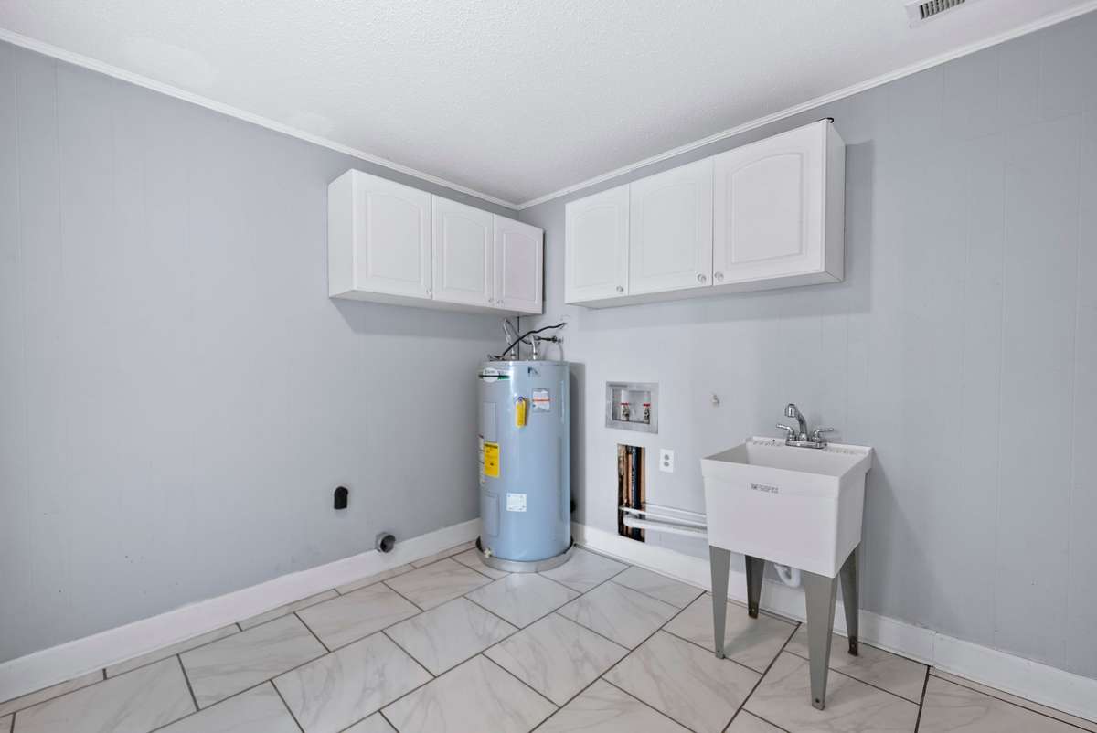 Huge laundry room with utility sink and cabinets for added storage.