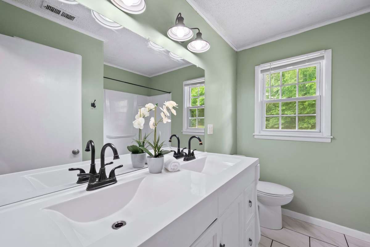 Secondary bathroom with double vanity and shower/tub combo.