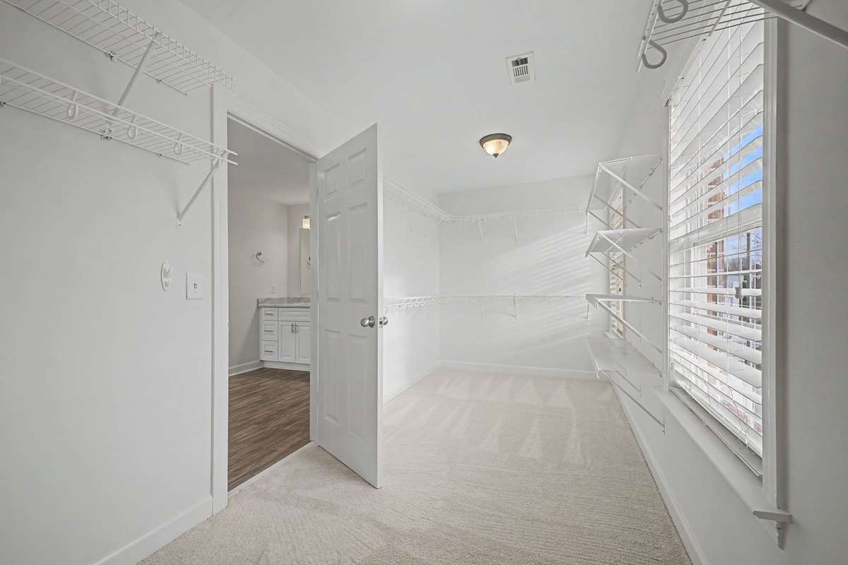 Large primary walk-in closet with window and abundant storage space