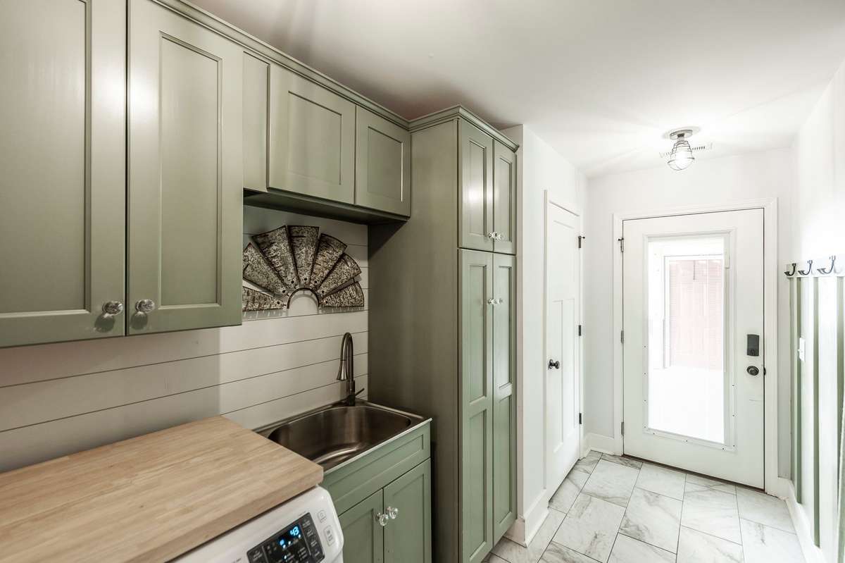 The laundry room features lots of cabinetry, a stainless-steel utility sink, and lots of closet storage.