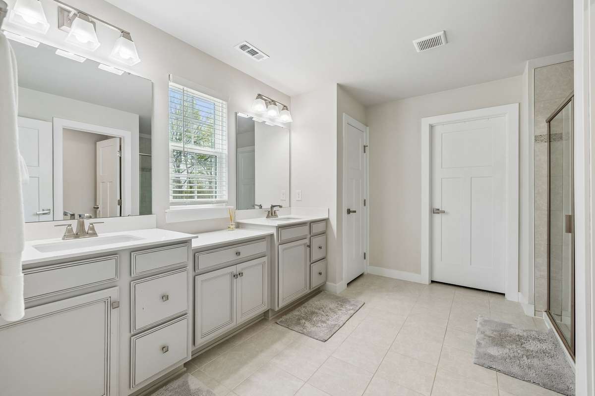 Primary bath with double sink vanity, tile floor, separate toilet area, and linen closet.