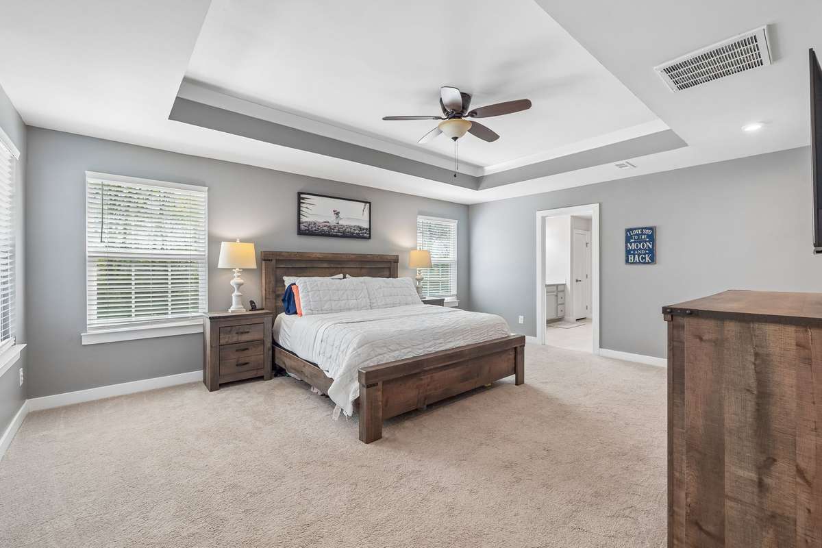 The primary suite features a tray ceiling with a ceiling fan, plenty of room for a king-size bed, nightstands, and just about anything else you want to add.