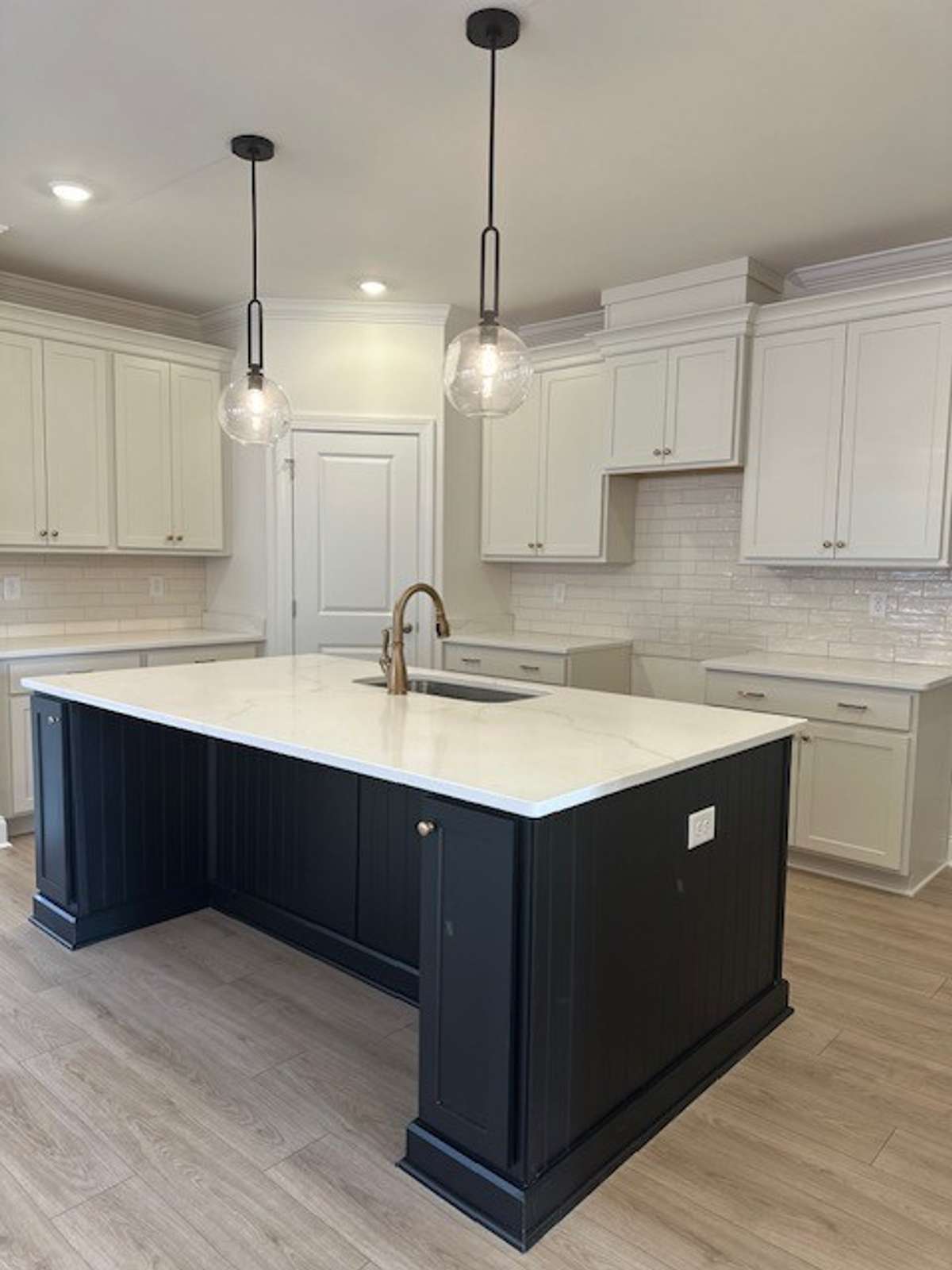 Your Kitchen is fabulous! It features: an island over 7 feet long, quartz countertops, gorgeous tile backsplash, trash roll out drawer, and (not yet installed) stainless steel appliances!