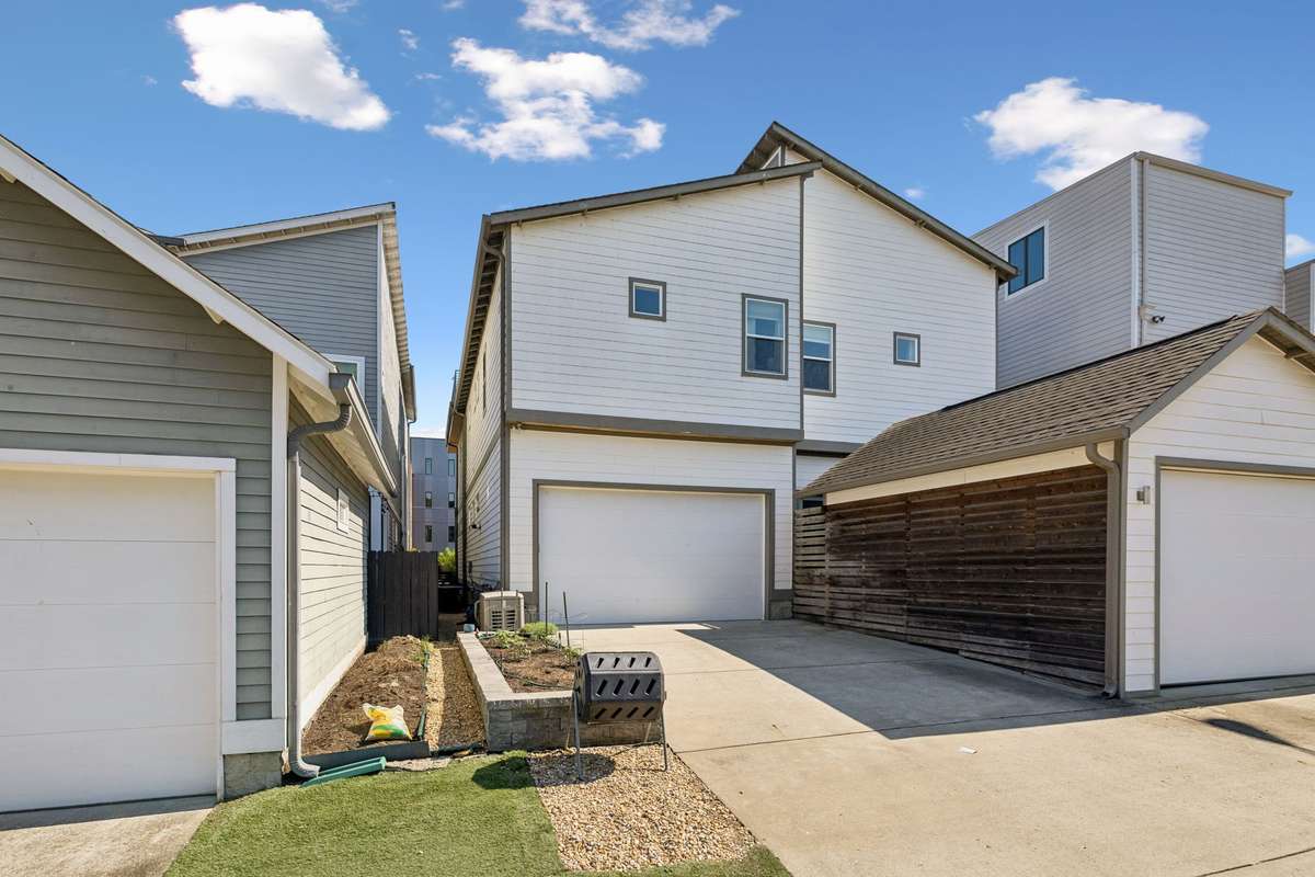 Back exterior featuring a two-car garage and private driveway perfect for extra parking if needed and raised beds for planting!