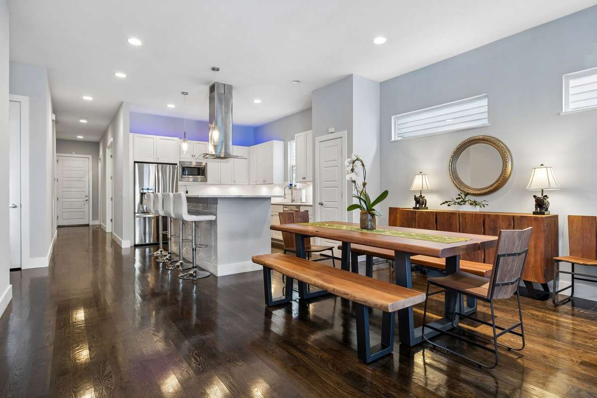 Open-concept living and dining area flows seamlessly into the kitchen, featuring hardwood floors, 10ft ceilings, a large island with bar seating, and modern finishes throughout.