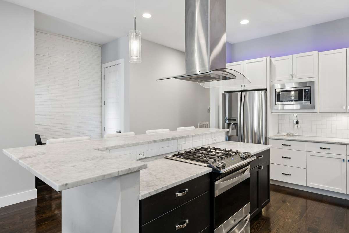 Another view of the kitchen showcases the stainless steel appliances, all of which remain. You’ll also notice a coat closet and a charming nook with a window above, perfect for a small desk or workspace.