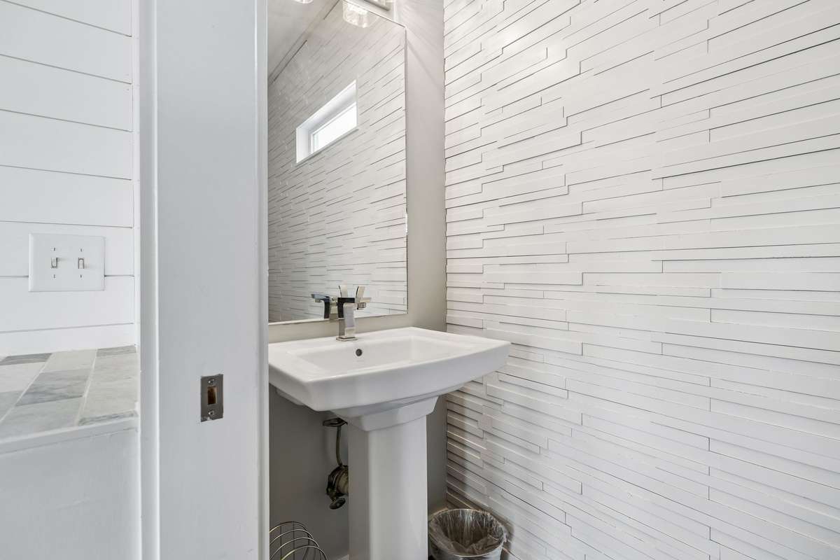 Powder room with a classic pedestal sink and stylish accent wall