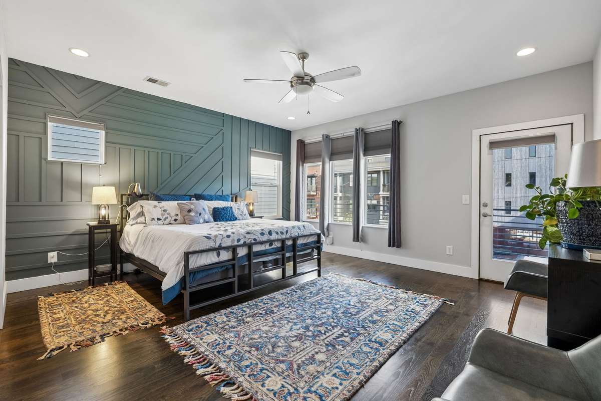 Spacious primary suite with abundant natural lighting features, hardwood floors, a statement accent wall, and a private balcony.