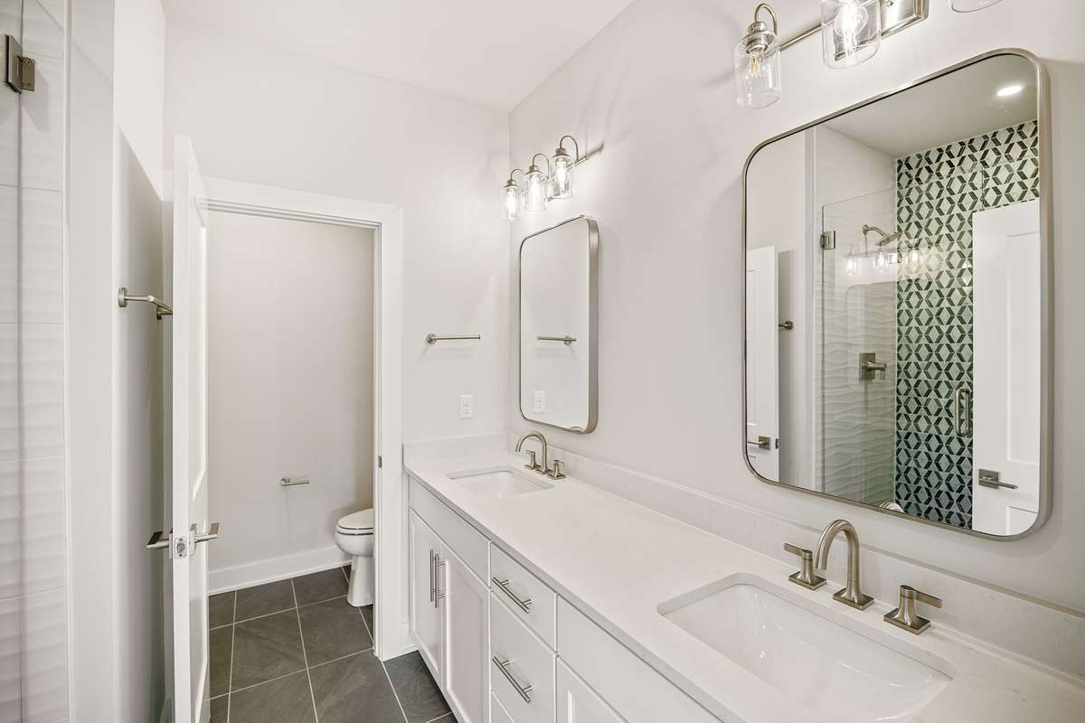The primary bathroom features dual vanities, water closet & stylish framed mirrors.