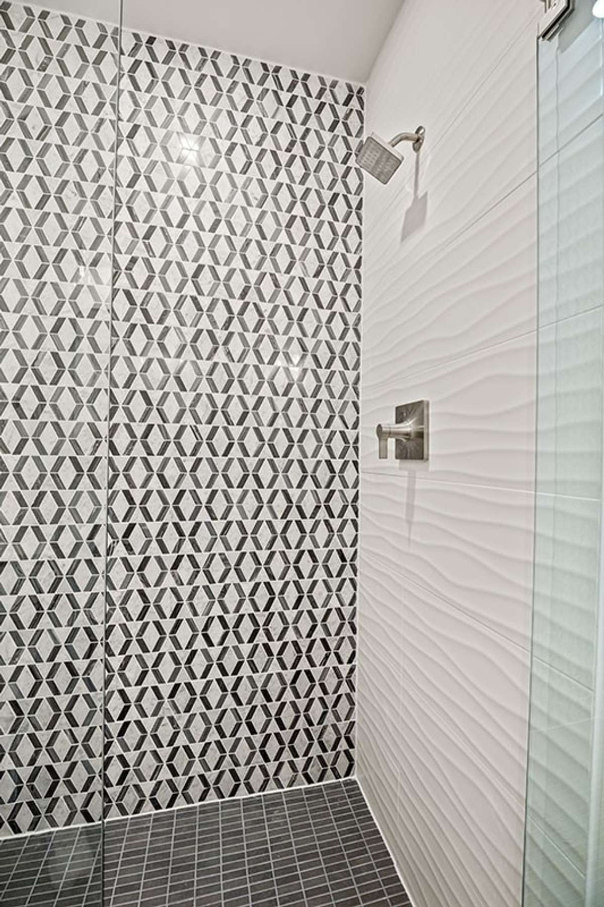 The primary bath's shower includes floor-to-ceiling tile and frameless glass.