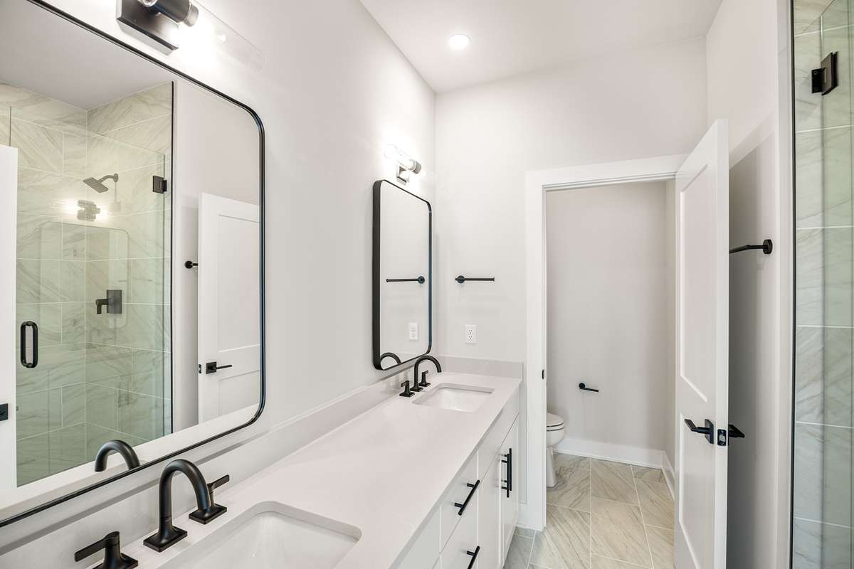 The primary ensuite bathroom features dual sinks, framed mirrors and designer selected tile.