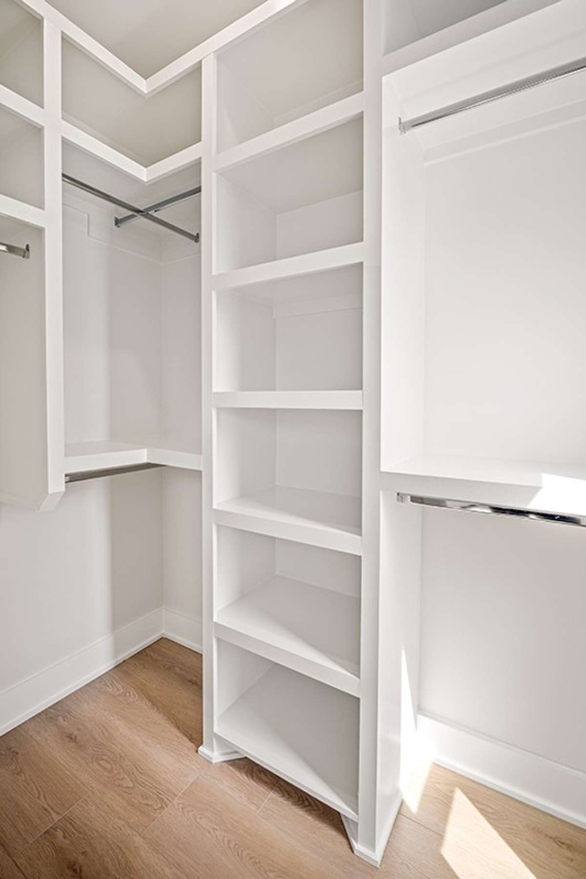 The primary suite's dual walk-in closets both feature custom wood shelving throughout.