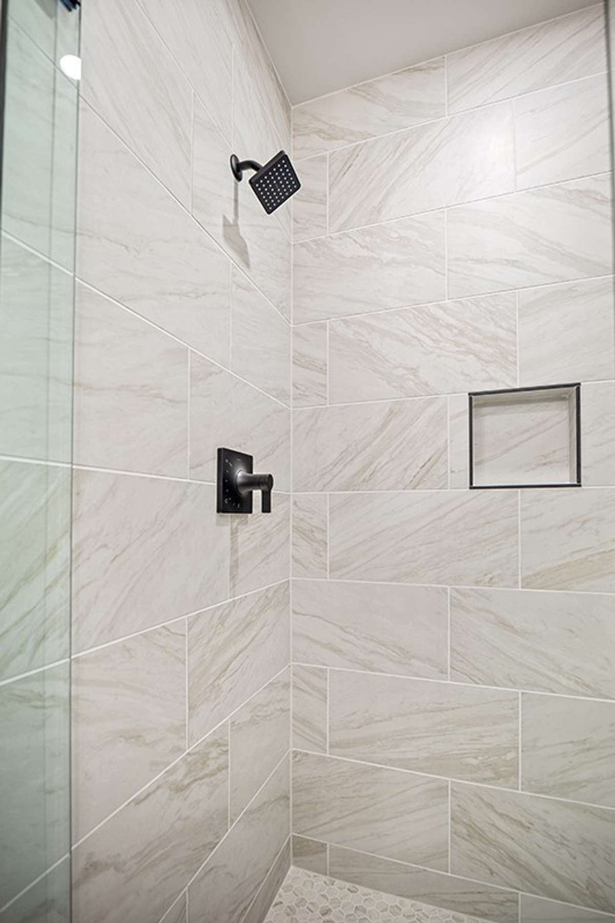 The primary bath's shower features frameless glass and gorgeous floor-to-ceiling ceramic tile