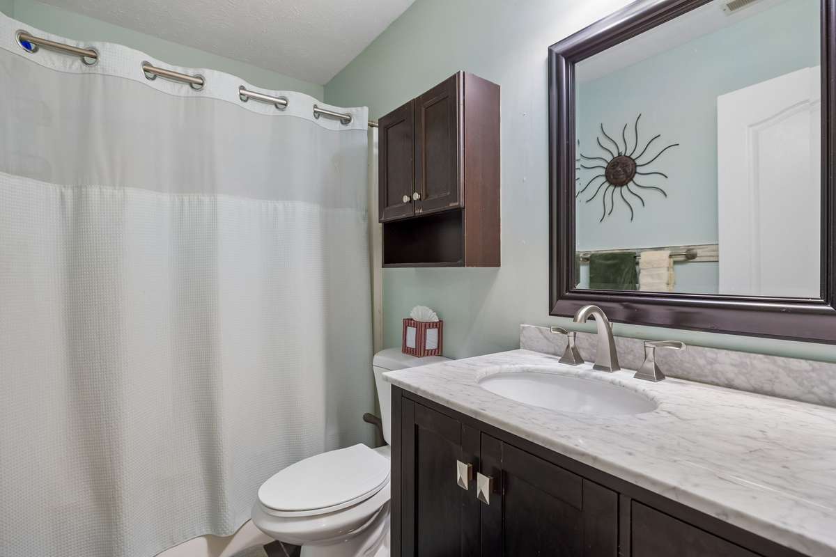 Guest bathroom with single vanity with marble counter, combo tub & shower, & tile floors. 2739 Oxford Hall Ave. Murfreesboro, TN 37128