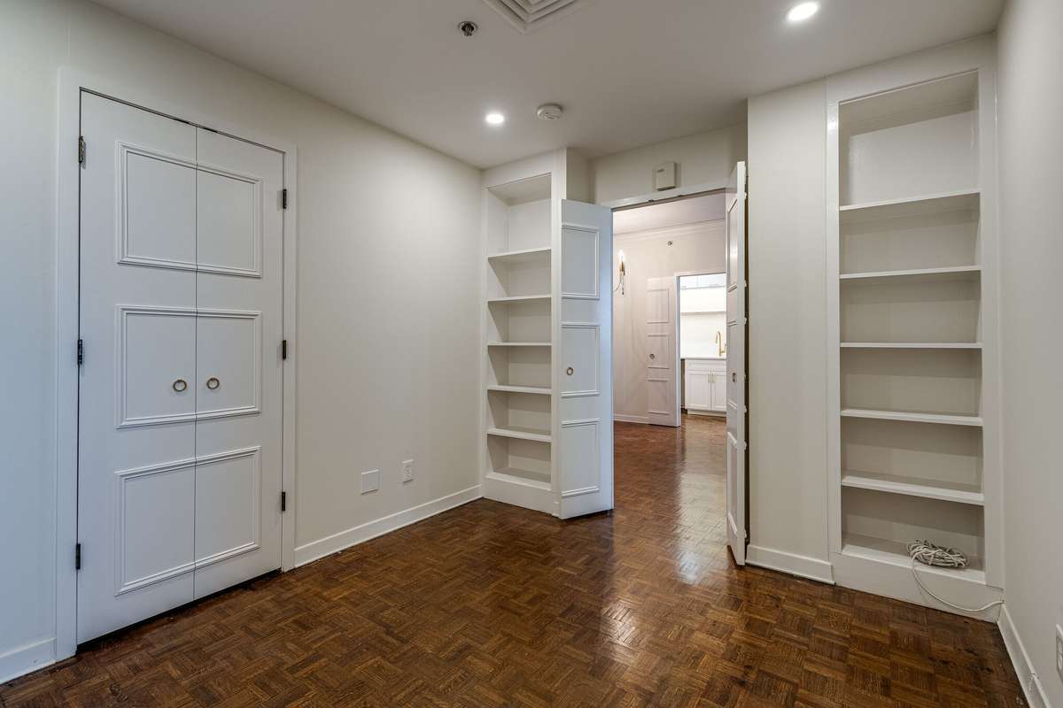 Perfect for a study, sitting room, guest bedroom, or music room, this inviting space features a newly added laundry closet, double built-in shelving, and custom matching doors accented with elegant gold hardware.