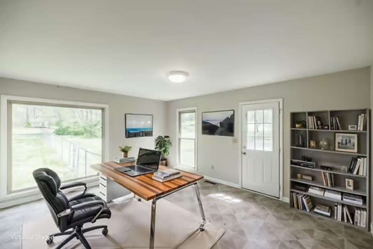 Virtual staging of the home office, huge picture window frames the enviable back yard