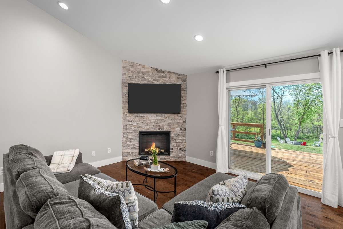 This bright living room features a beautiful stone fireplace and slider opening to a spacious deck. The recessed lighting is fantastic but you will love all of the natural light in this room!