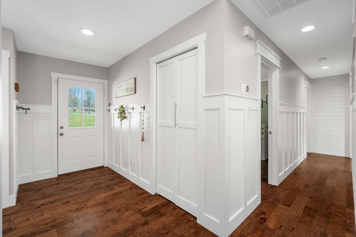 Welcoming entry hall with wainscoting, hardwood floors, recessed lighting, and spacious double-door closet.