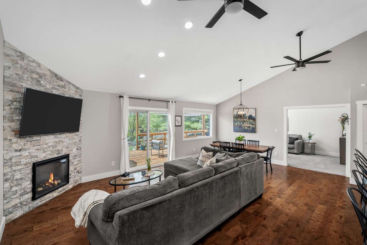 Open-concept living and dining with vaulted ceiling and a sliding door opening to a spacious deck.