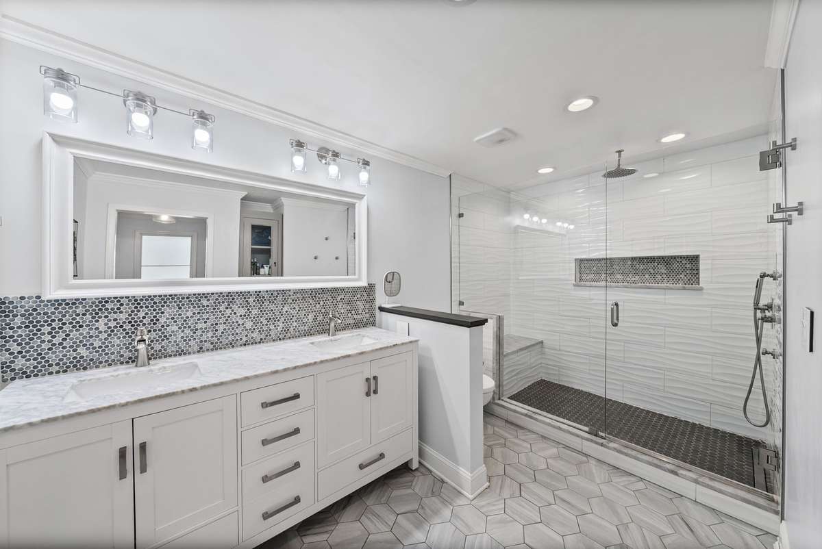 The Primary bathroom offers a renovated walk in shower complete with bench, double sinks, heated floors, and built in shelving.