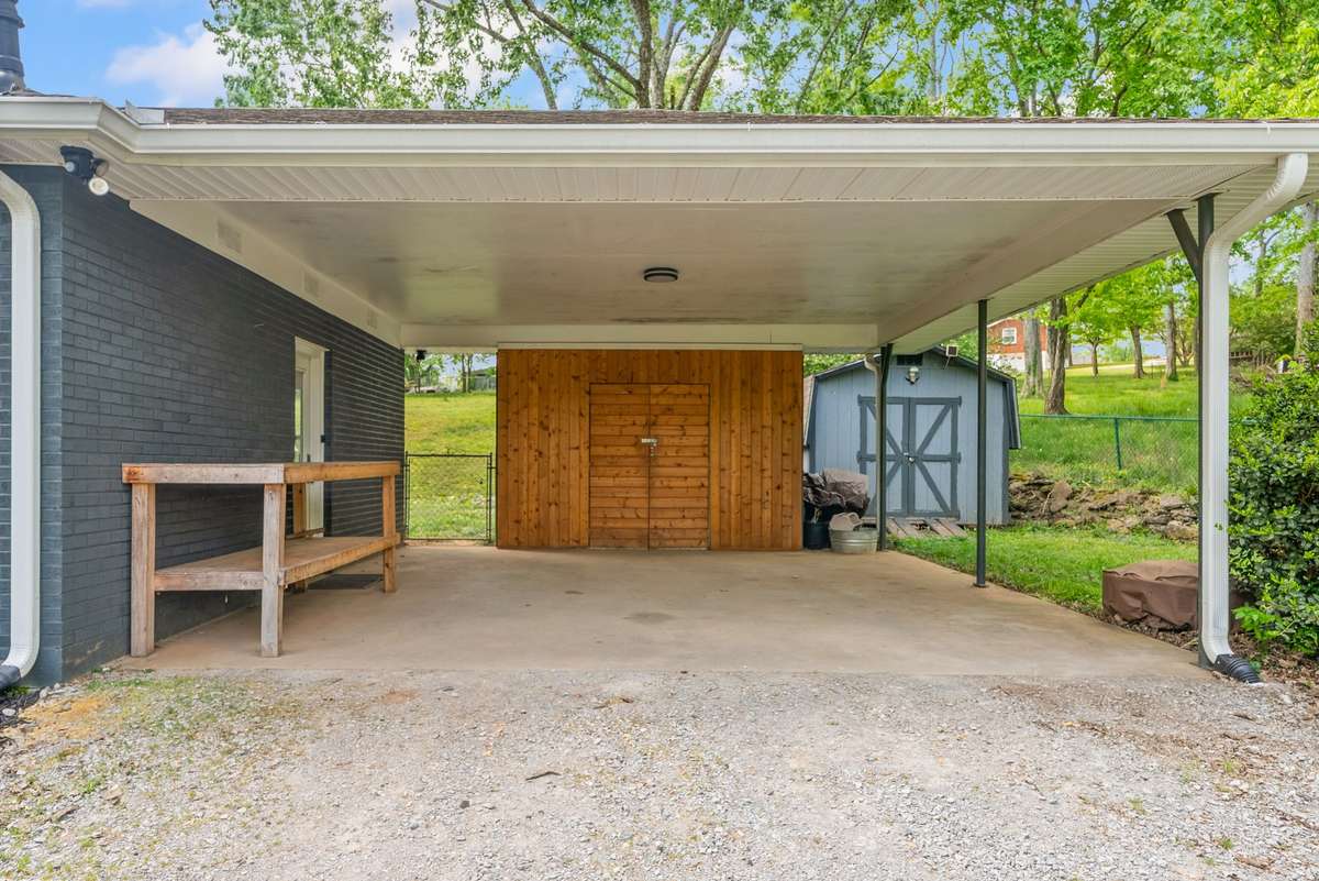 Carport offers storage area, side entry into the den, gate into the back yard, and additional storage in the conveying shed.