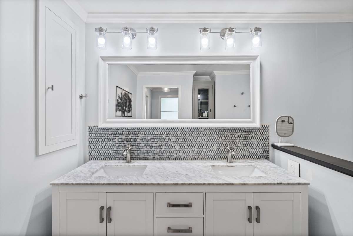 The Primary bathroom offers a renovated walk in shower complete with bench, double sinks, heated floors, and built in shelving.