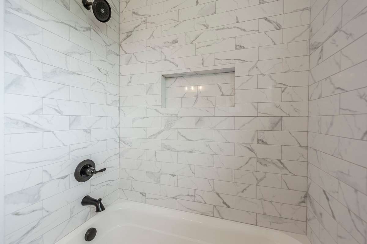 A tub/shower combination with stylish tile surround creates a bright, polished space that is both functional & inviting.