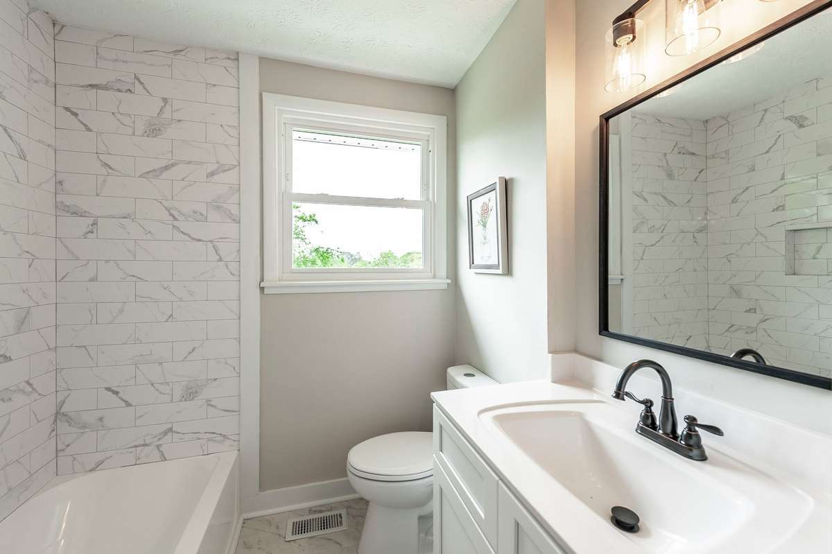 The fully renovated bathroom features a clean, modern design with crisp white cabinetry & updated fixtures for a fresh, timeless feel.