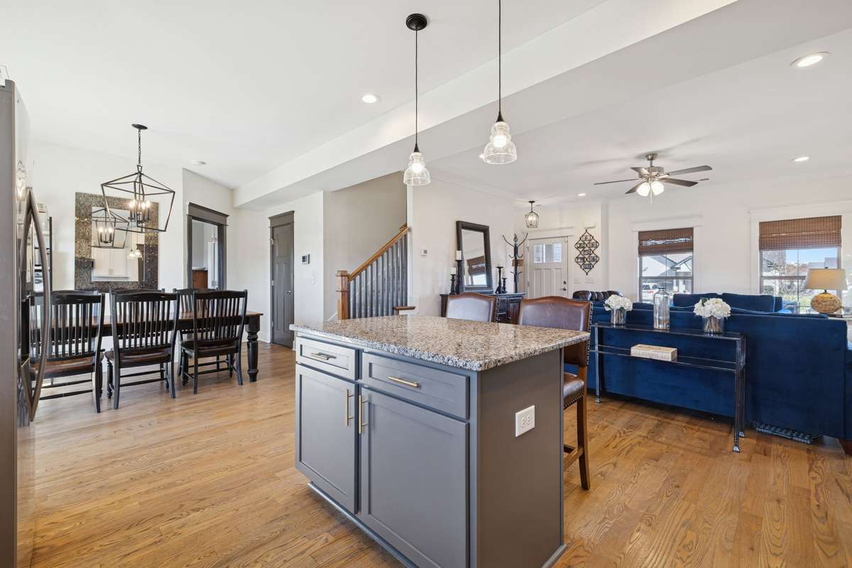 The kitchen vantage point shows access to the living room, the stairs that lead up, the dining area, and the doorway to the half bath and the downstairs primary bedroom suite.