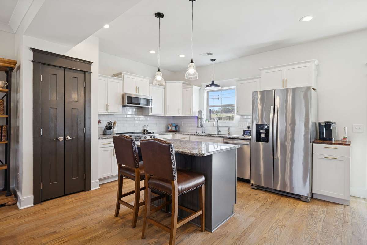 Beautifully accented with pendant lighting, the kitchen bar offers the perfect spot for casual snacks or chatting with the home’s chef. Double doors open to a spacious pantry with ample storage for dry goods and more.