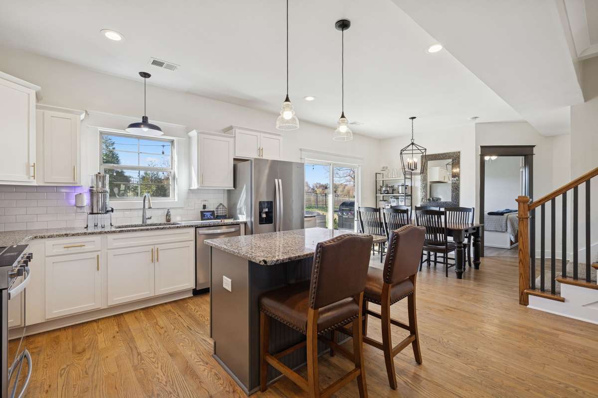 This home is on trend with its granite countertops, white subway tile backsplash, gold hardware, and dark colored island.  Recessed and pendant lighting provide ample radiance to inspire your culinary creations.