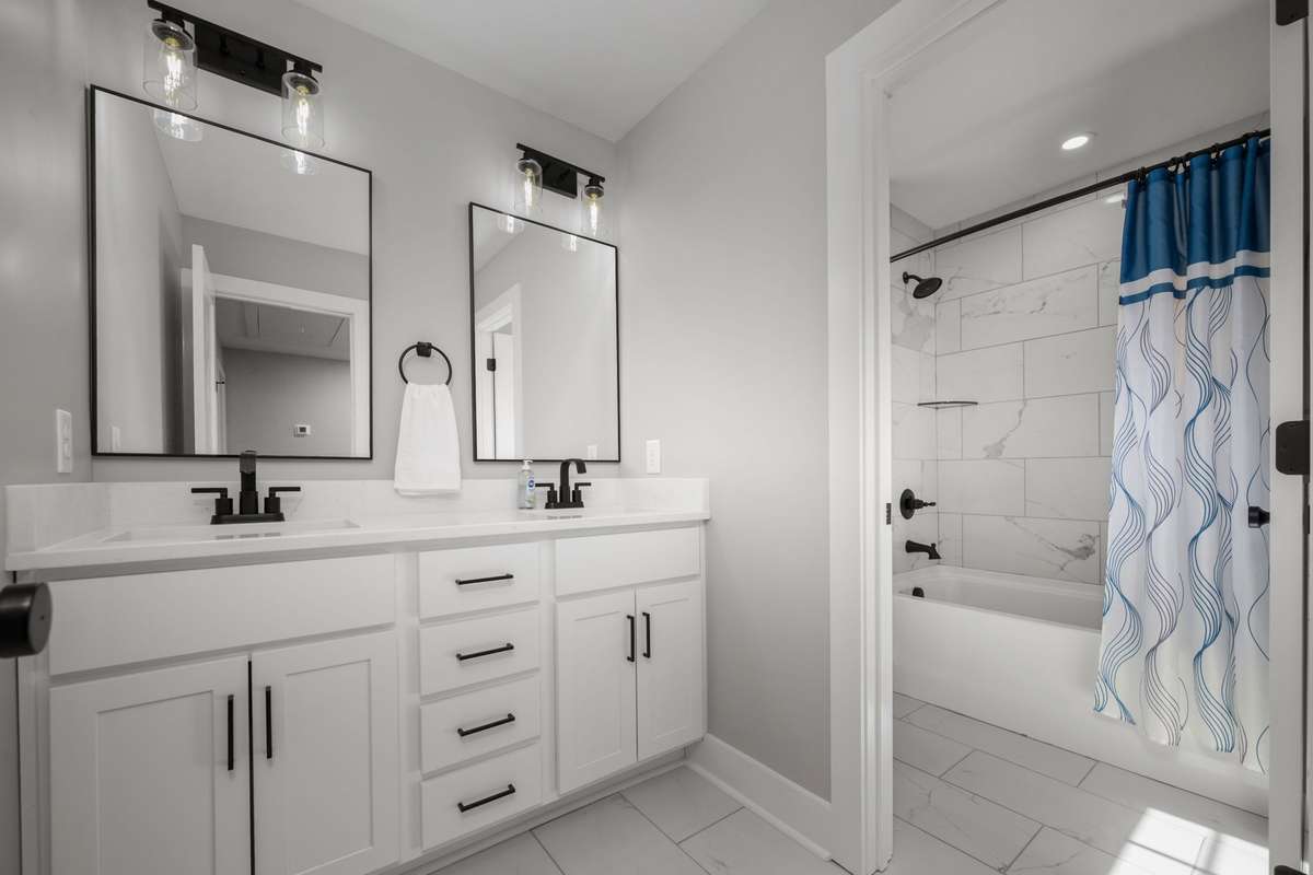 Upstairs bathroom with double vanities and a separate tub and toilet area for added privacy.