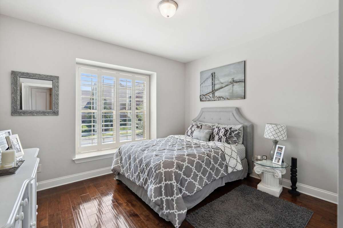 Bedroom #2 features large window, plantation shutters, and hardwood floors.