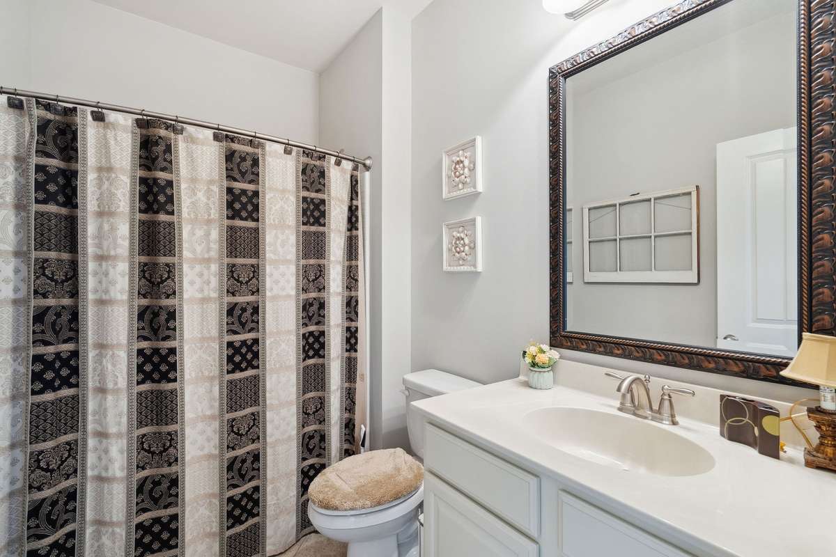 2nd Full bath (downstairs) with a shower/tuh combination, white cabinets, and framed mirror.