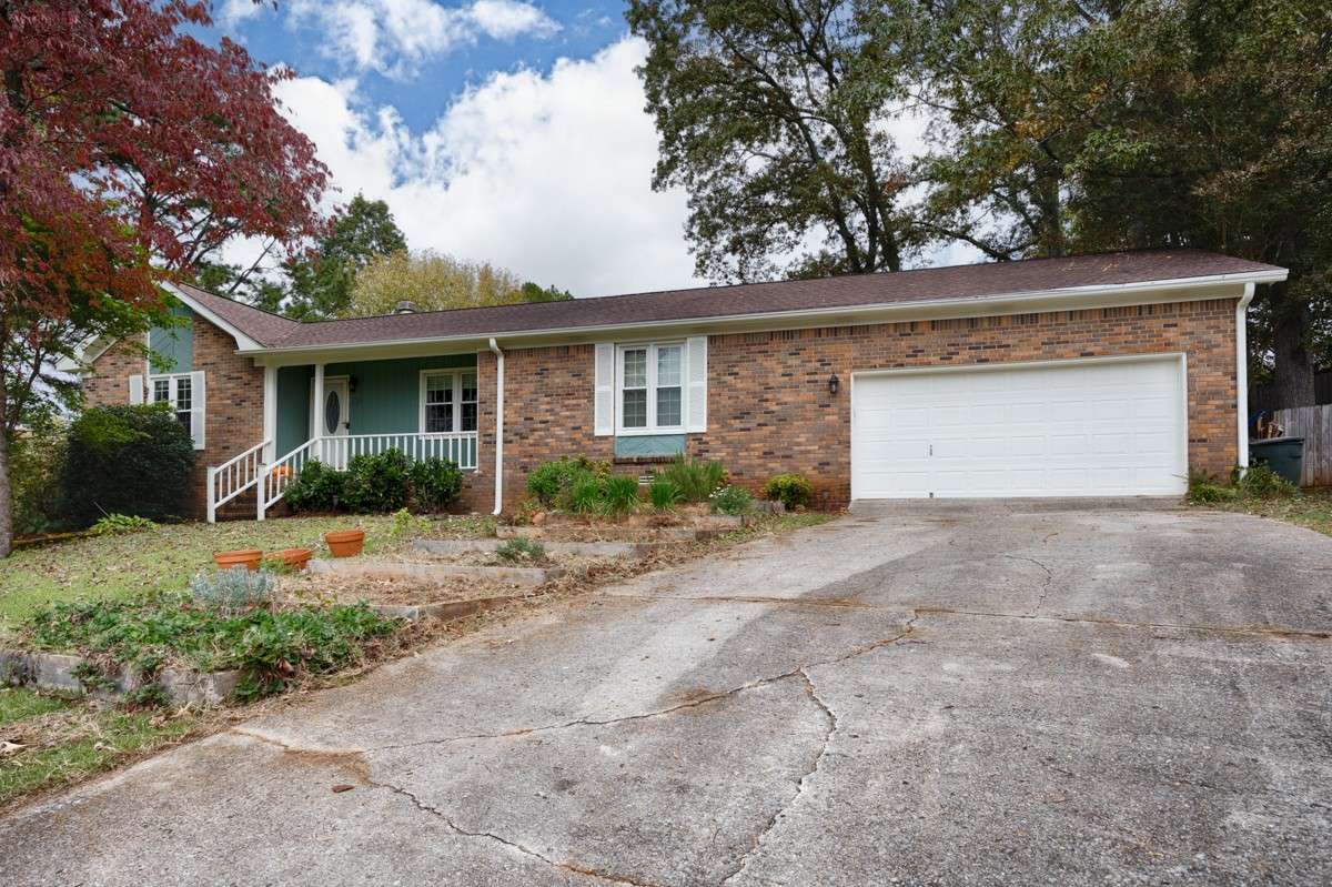 Front of house- covered front porch, full brick, landscaping, front entry 2-car garage with single rollup door, concrete driveway and sidewalk, gutters