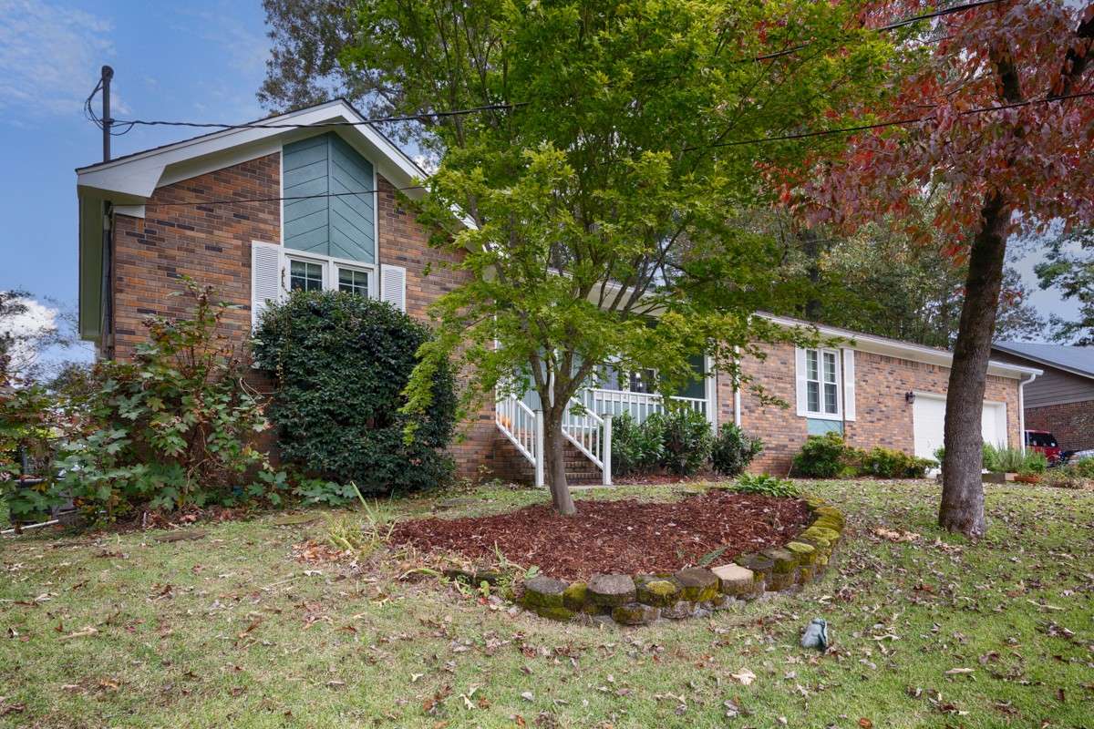 Front of house- covered front porch, full brick, landscaping, front entry 2-car garage with single rollup door, concrete driveway and sidewalk, gutters