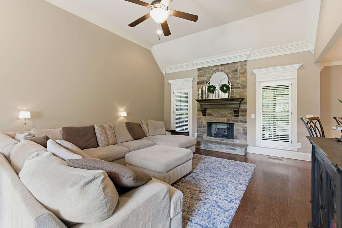 The great room features a beautiful gas stone fireplace with logs and opens to the kitchen area.