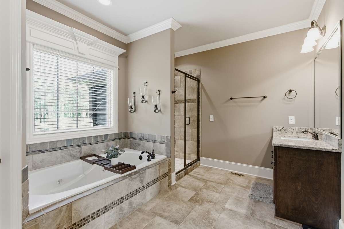 The primary bath features a tub that has a window overlooking the private backyard. It has 2 vanities, a tiled shower, and a separate water closet for privacy.