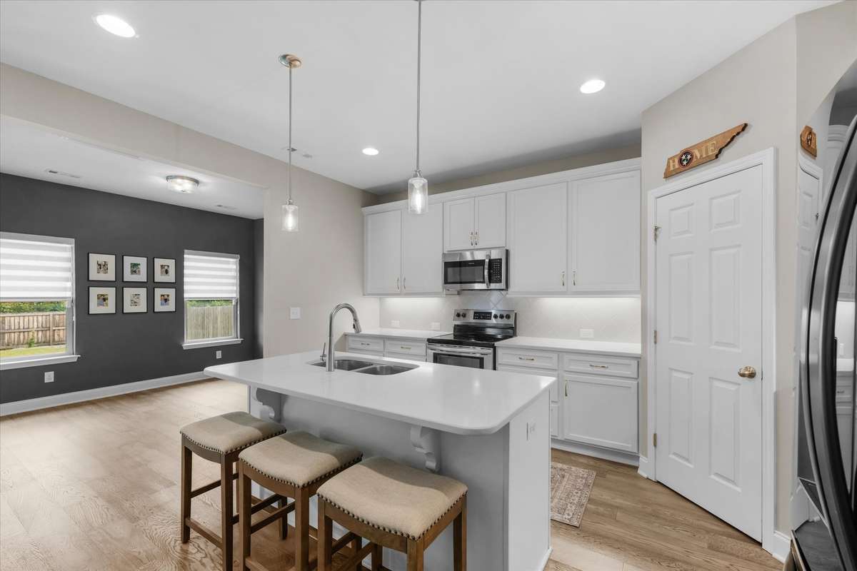 Kitchen is spacious with quartz counters and gleaming white cabinets.