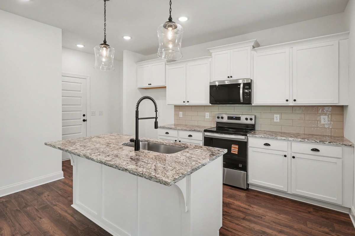 Spacious open-concept layout with oversized island, upgraded faucet, and seamless flow into the living area—perfect for entertaining.