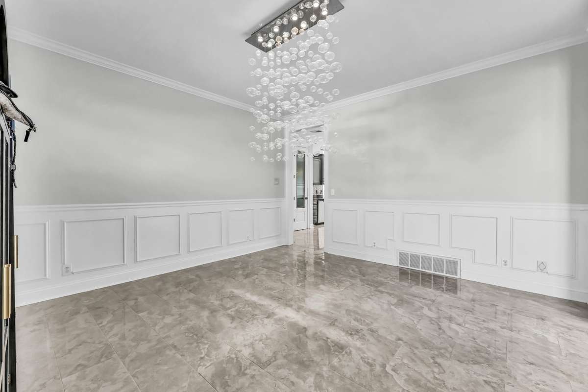 The formal dining room with modern lighting + tile floors + wainscoting.