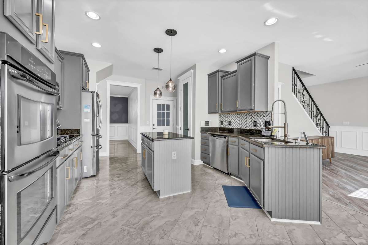 Other kitchen features include tile backsplash, granite counters, tile flooring, updated lighting, & gold accents.