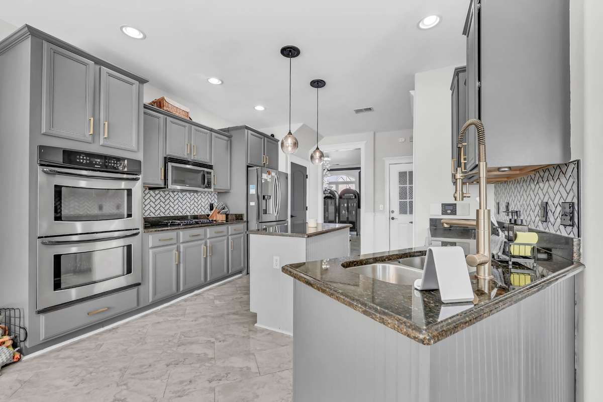 This gorgeous kitchen includes  stainless steel double ovens, gas range, microwave, refrigerator, & dishwasher.