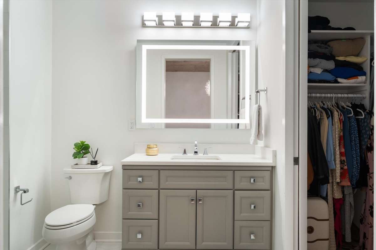 Lighted vanity mirror in bath with  new cabinetry and quartz countertop