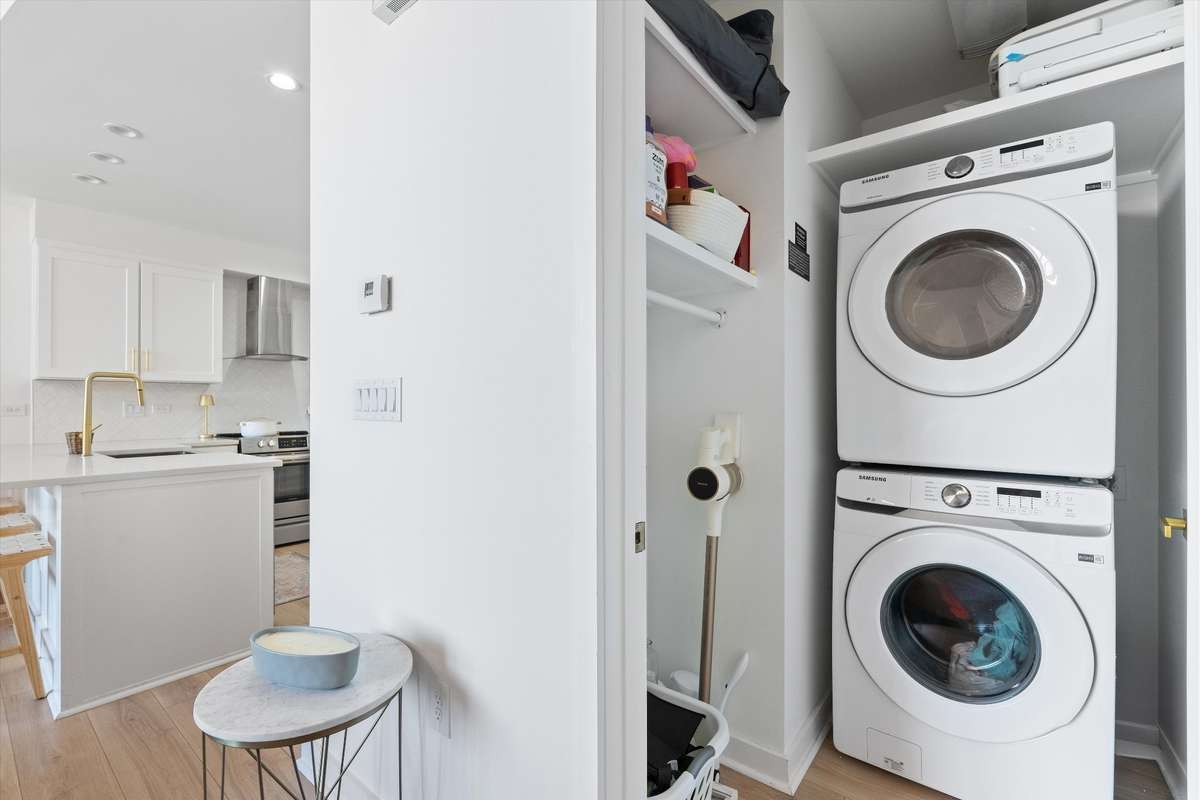 New washer and dryer in laundry room with custom cabinetry hanging rod and storage