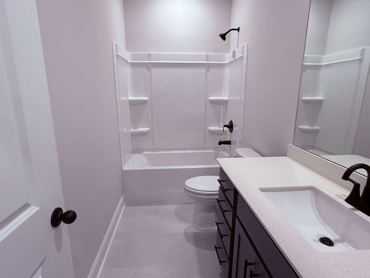 The second bathroom features tile flooring and quartz countertops, combining durability with a clean, modern design.