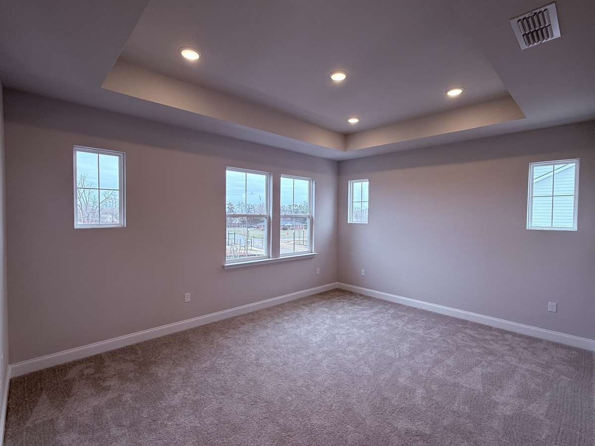 The primary bedroom, located on the 2nd floor, features a tray ceiling that adds architectural interest and a sense of spaciousness. Strategically placed windows allow natural light to pour in, creating a bright, welcoming, and serene retreat.