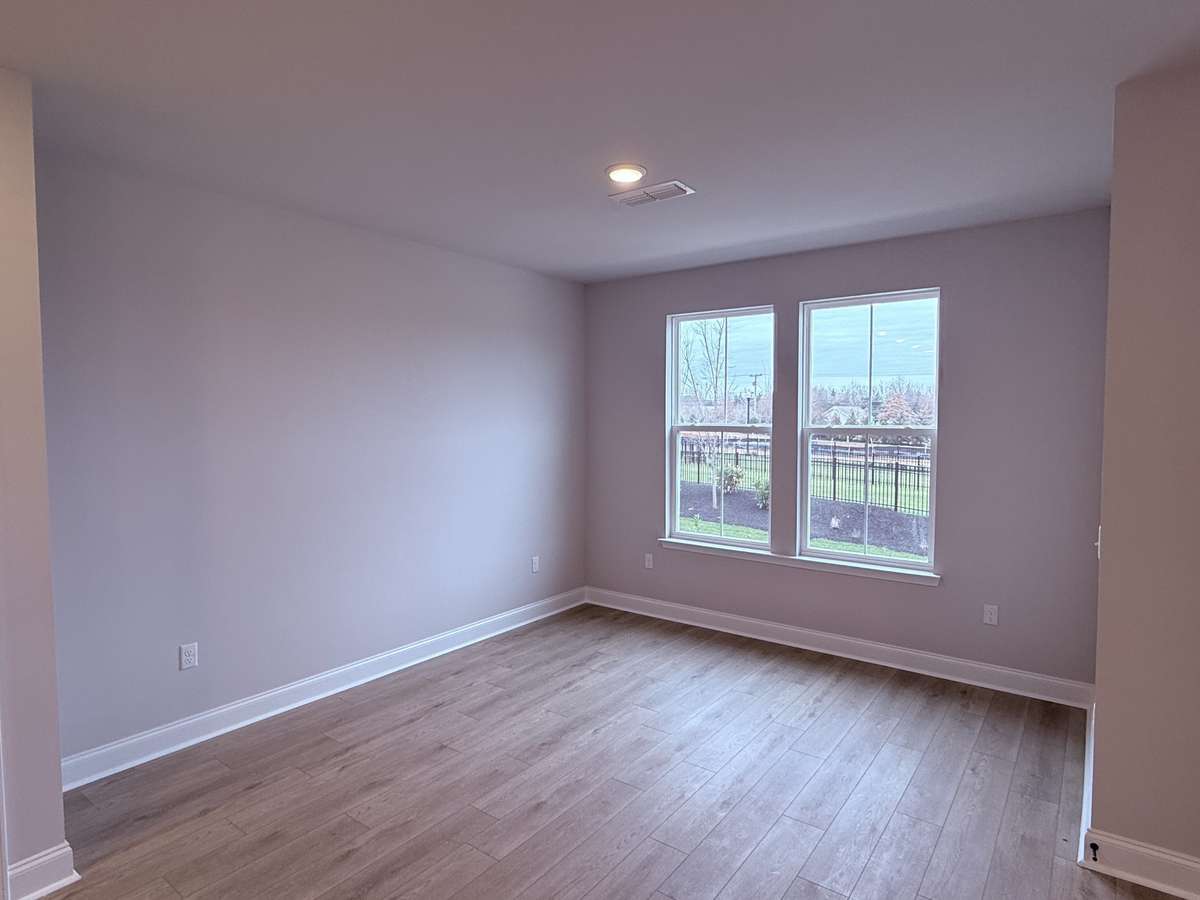 Located at the front of the home, the dining room features large windows that overlook the beautifully landscaped community dog park and green space, filling the room with natural light and offering a peaceful view.