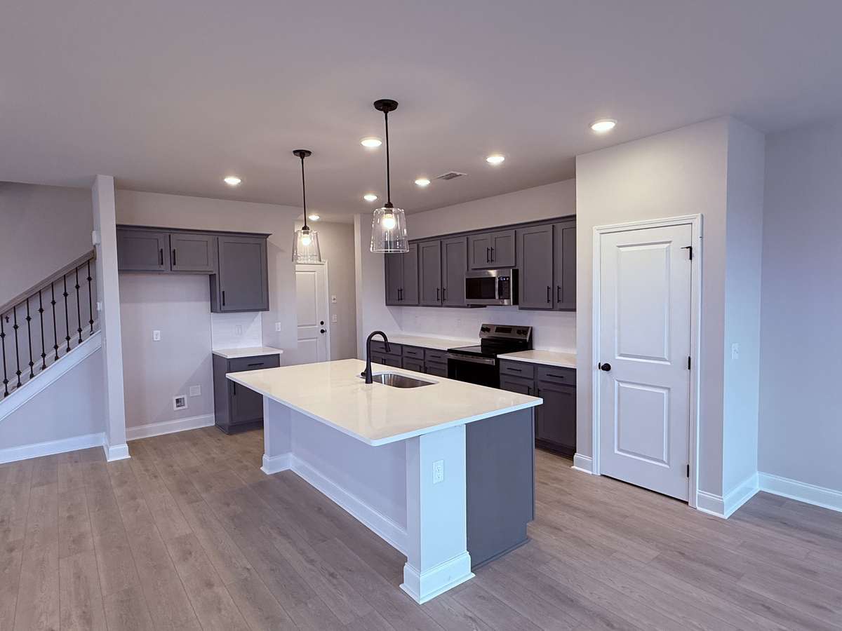 The kitchen features gray soft-close cabinetry, quartz countertops, and a stylish tile backsplash — combining durability, function, and modern appeal in one beautifully designed space.