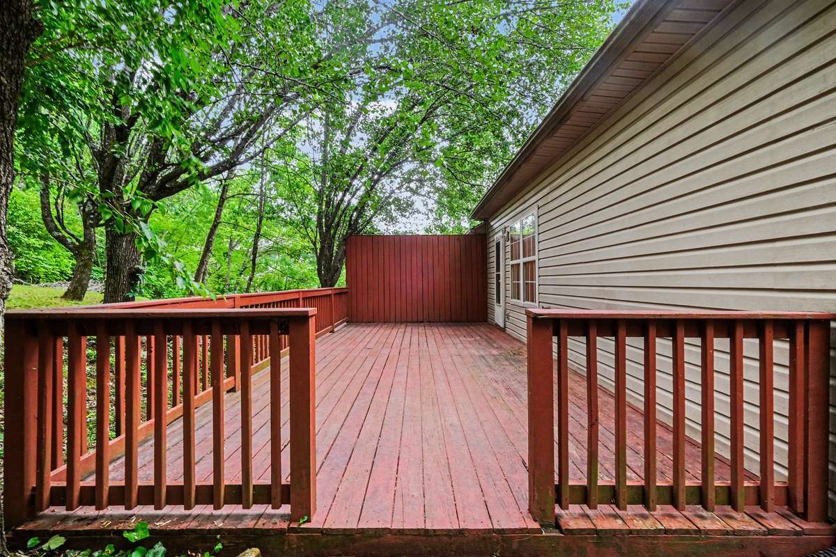 Private back deck overlooking a serene, wooded common area. This spacious outdoor living space is ideal for relaxing and enjoying the mature greenery that surrounds this move-in-ready home.